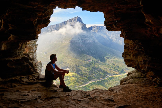 photo of man sitting on a cave 1659437