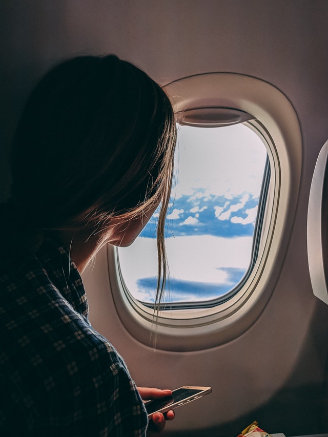 person holding smartphone riding airplane 2033343